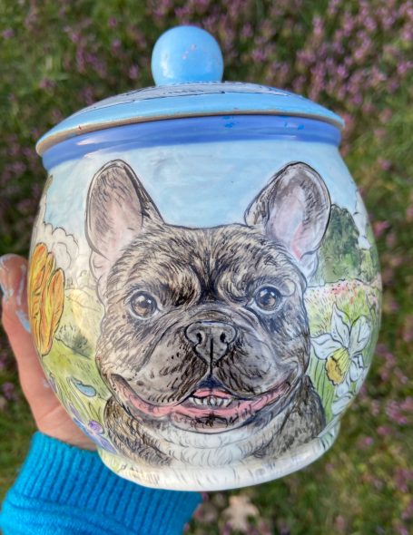 handbemalte Urne für eine Französische Bulldogge mit Blumen im Hintergrund
